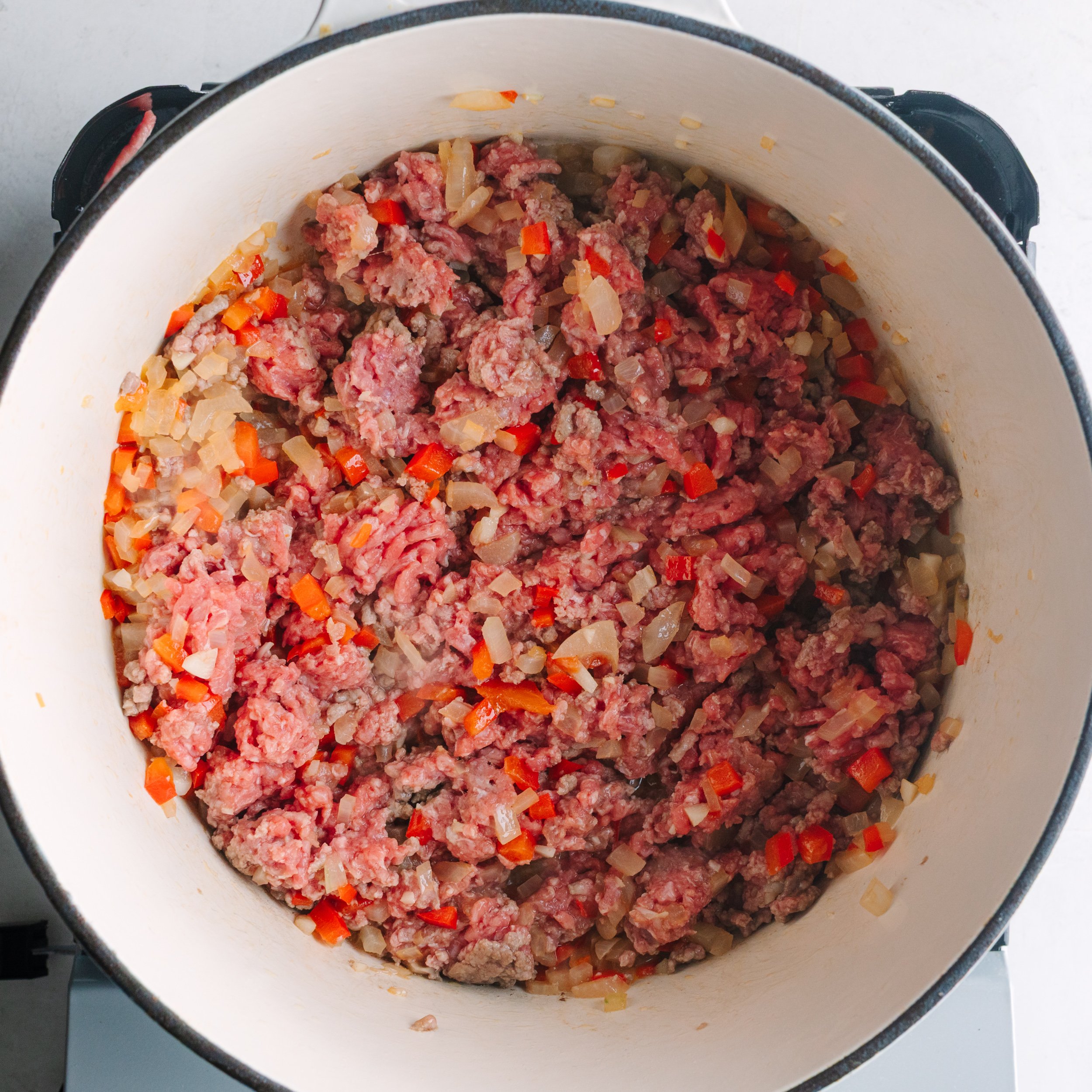 Cooking ground beef with peppers, onions, and garlic in a dutch oven.