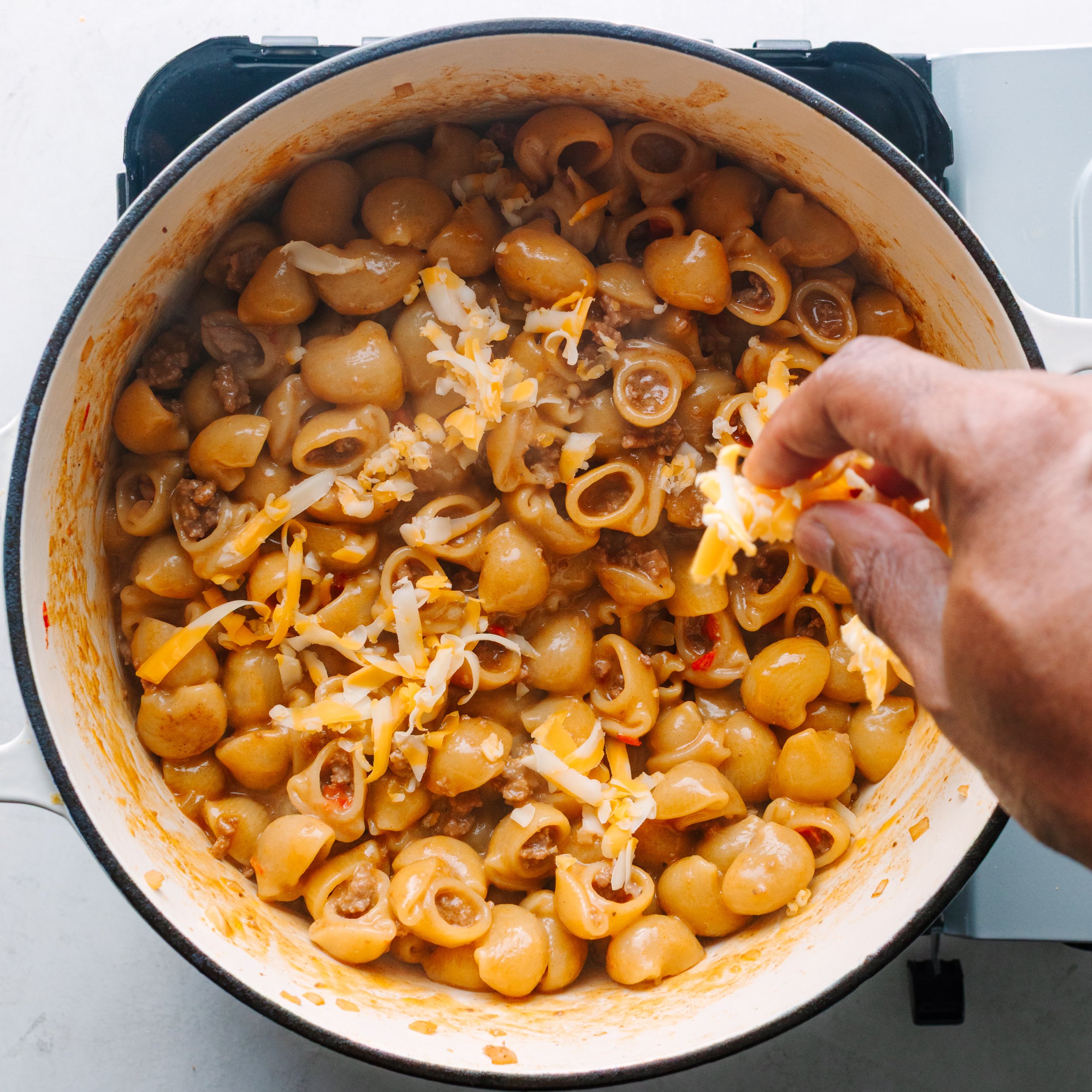 Adding shredded cheese to the pasta
