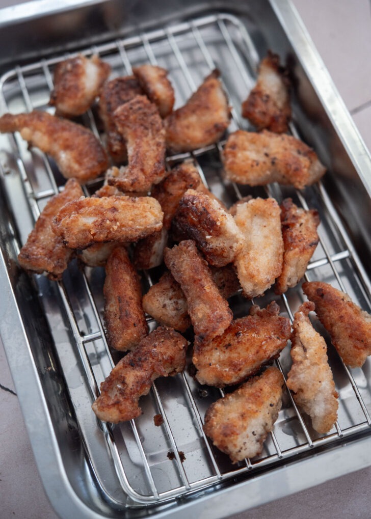 Crispy golden pork pieces resting on a wire rack after frying
