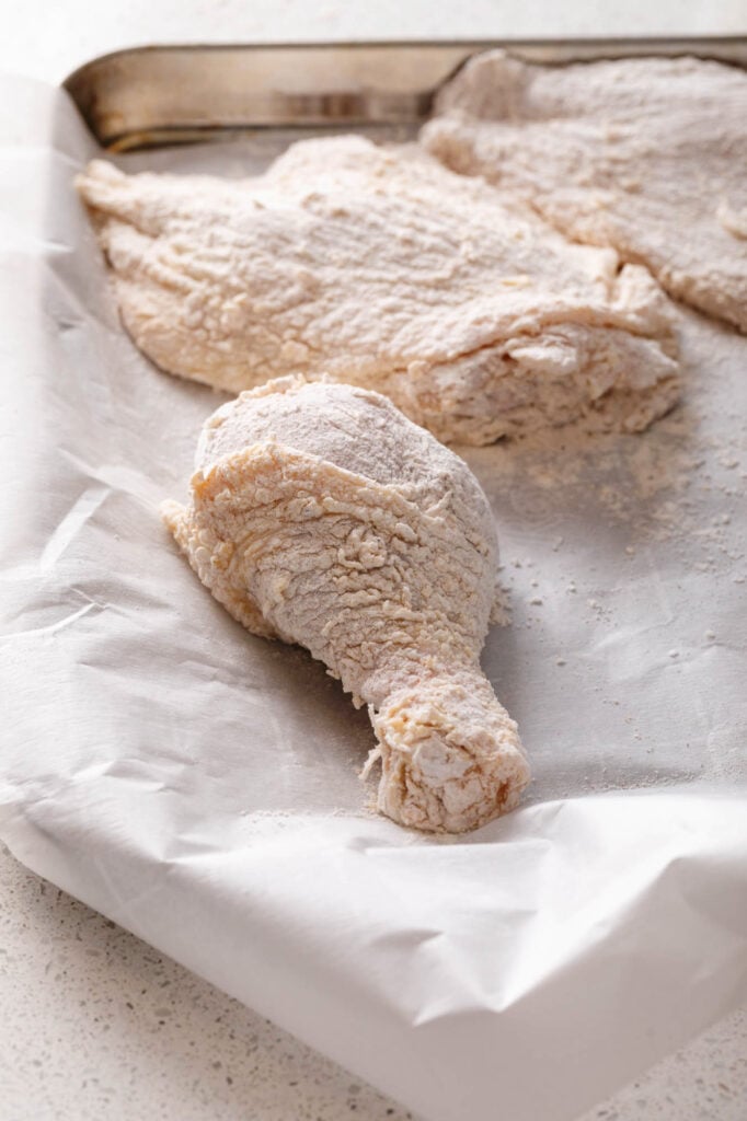 floured chicken on a parchment lined sheet pan