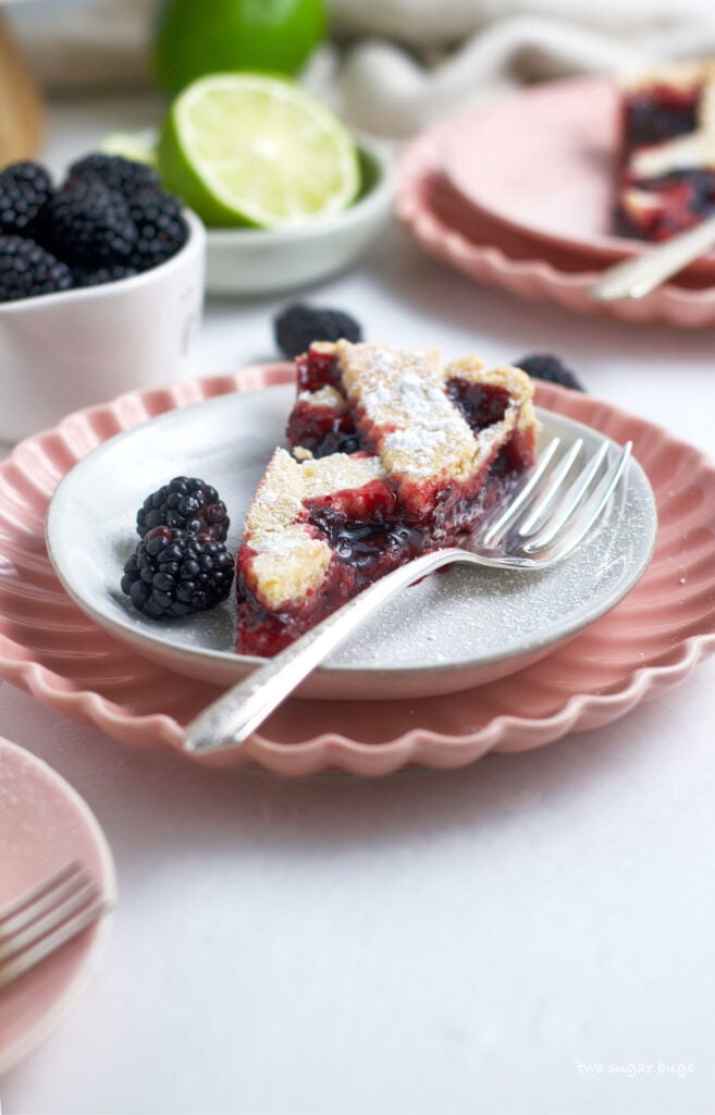 slice of crostata on a plate with a fork and blackberries