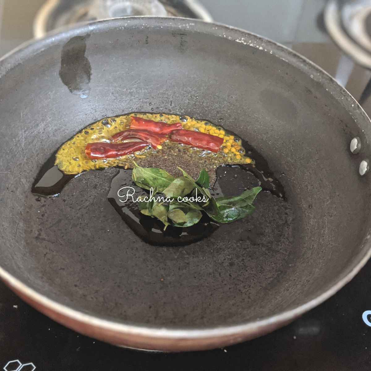 Mustard seeds, cumin seeds, fenugreek seeds, dry red chillies and curry leaves in oil in a wok