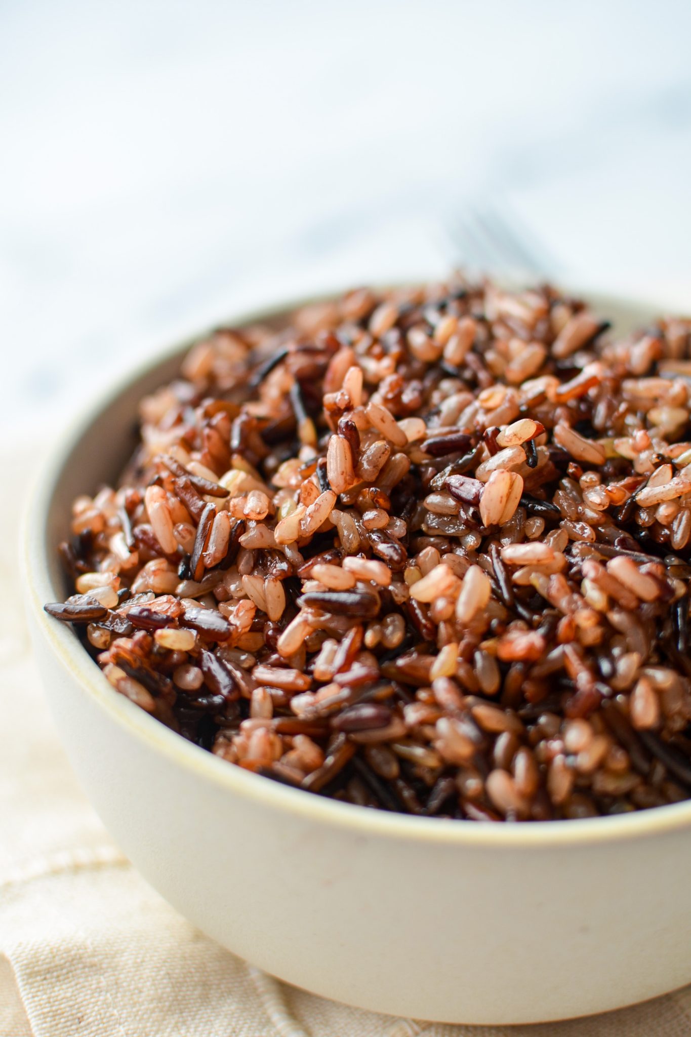 A bowl of wild rice on a cloth napkin.