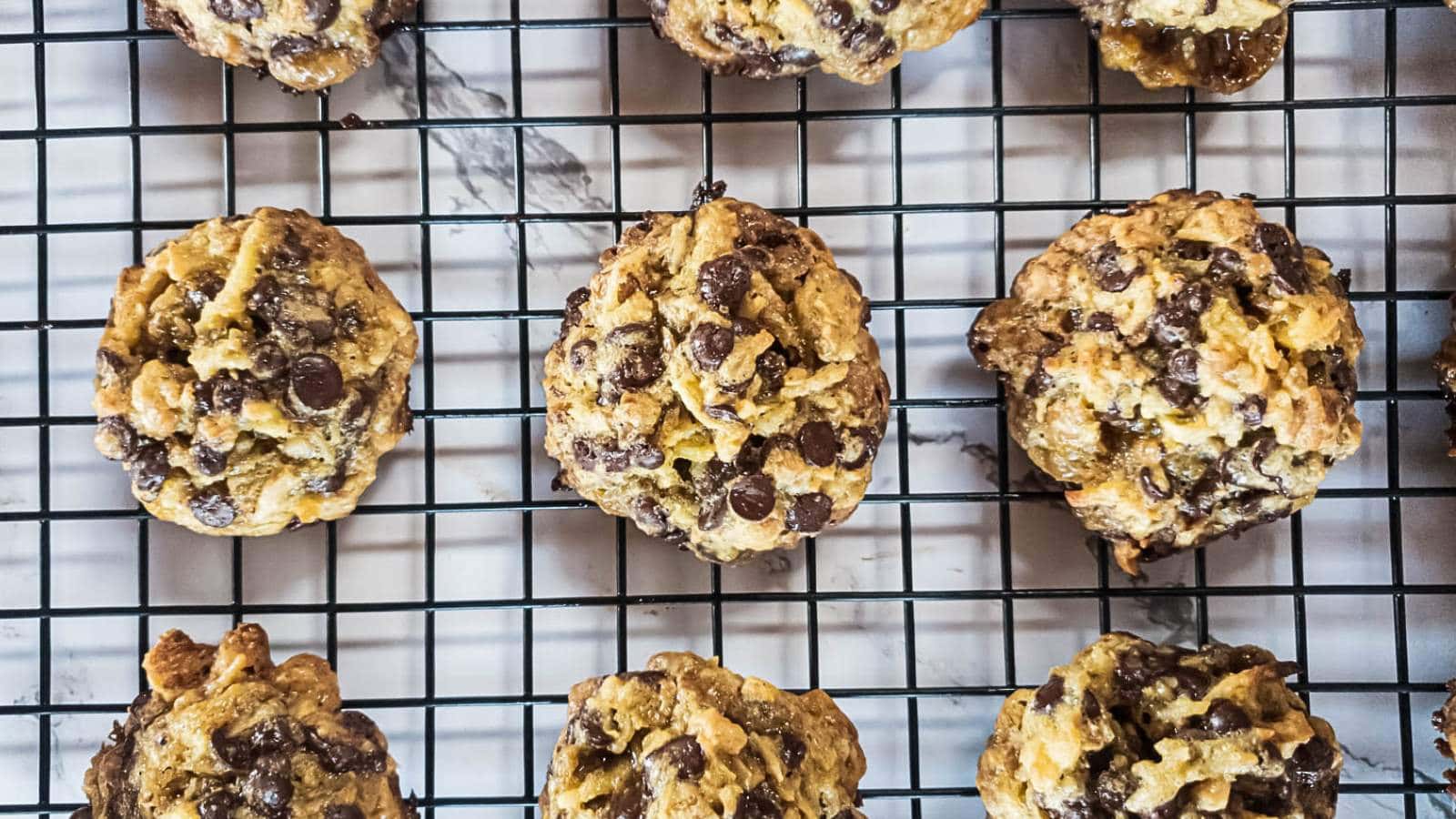 Keto magic cookies cooling on a black wire rack over a marble surface.