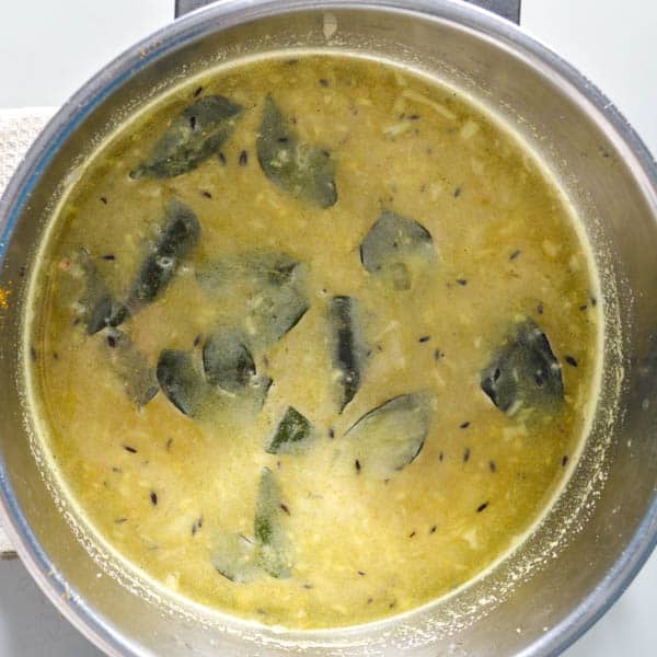 Curry leaves, lentils and stock in a pot