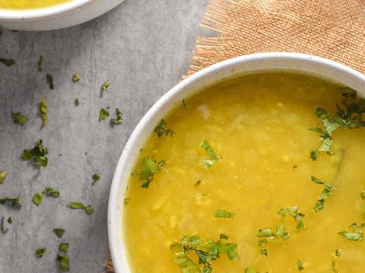 Two bowls of yellow soup on burlap