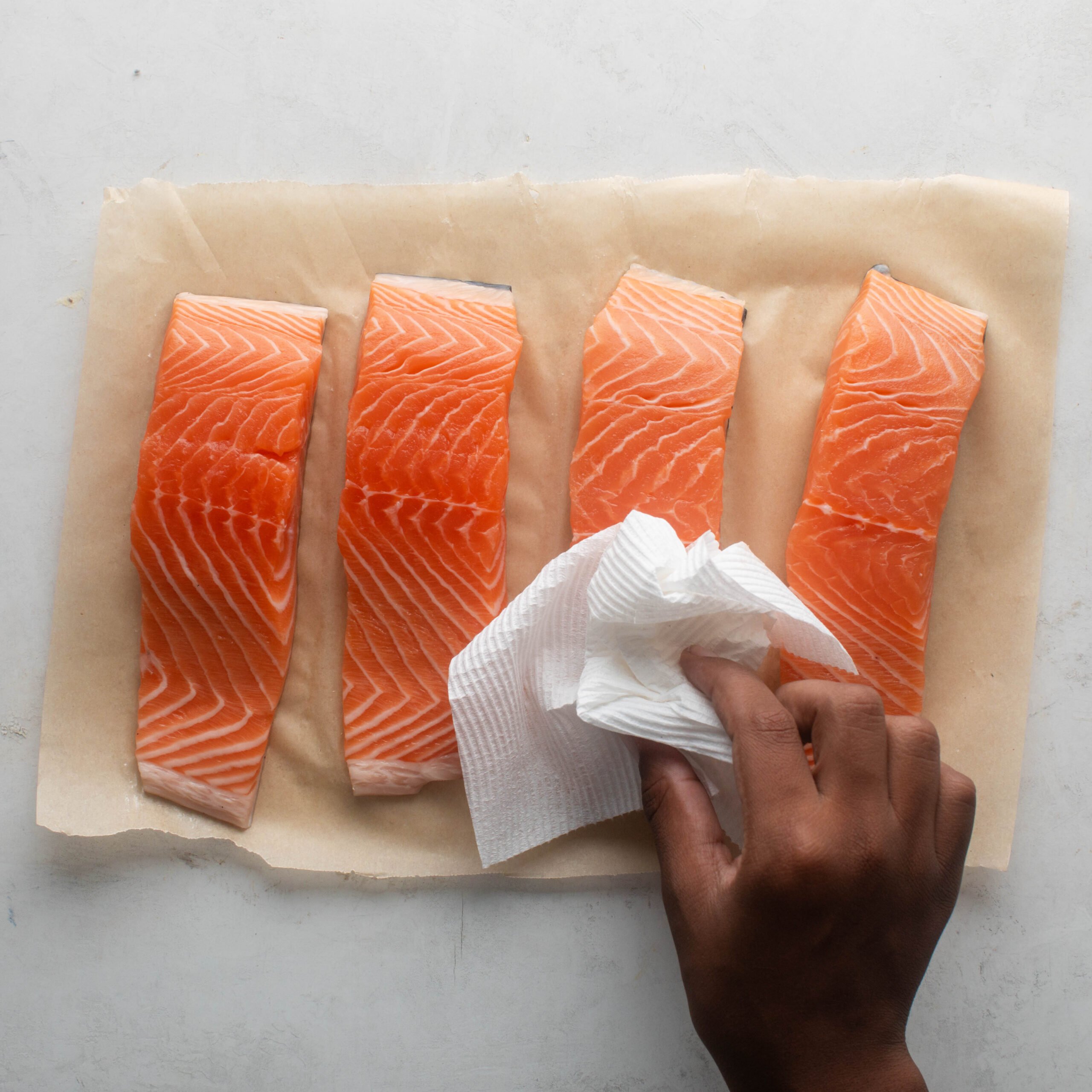 Patting dry 4 pieces of skin on salmon with a paper towel. 