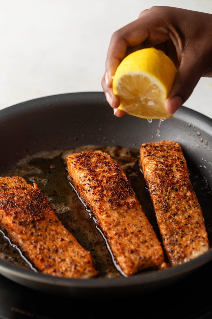 squeezing fresh lemon juice over cooked salmon filets. 