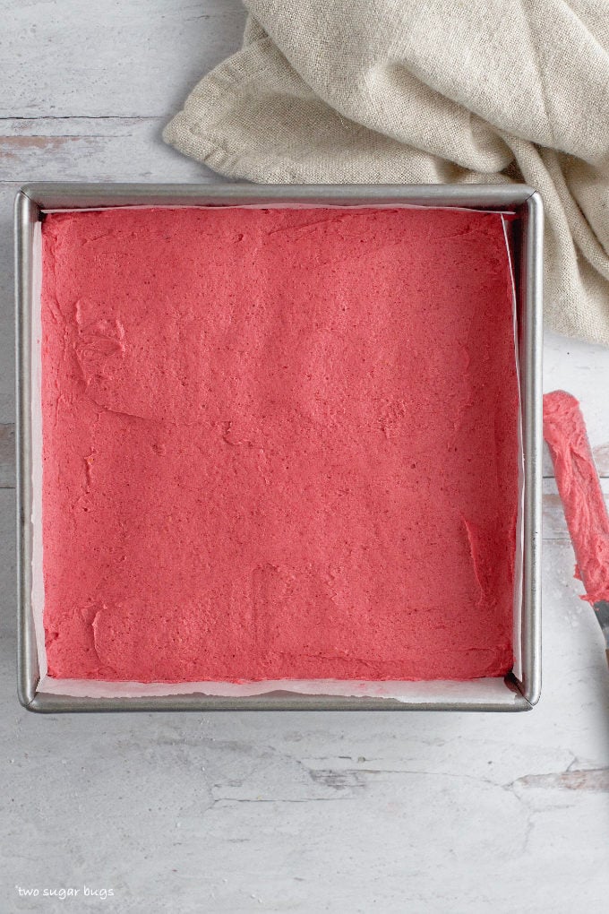 smoothed raspberry buttercream layer in a baking pan
