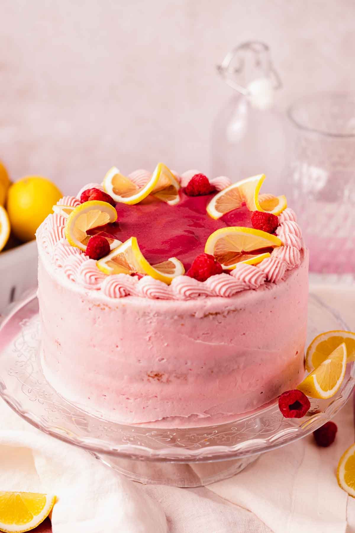 cake with pink raspberry frosting and fresh lemon slices on top