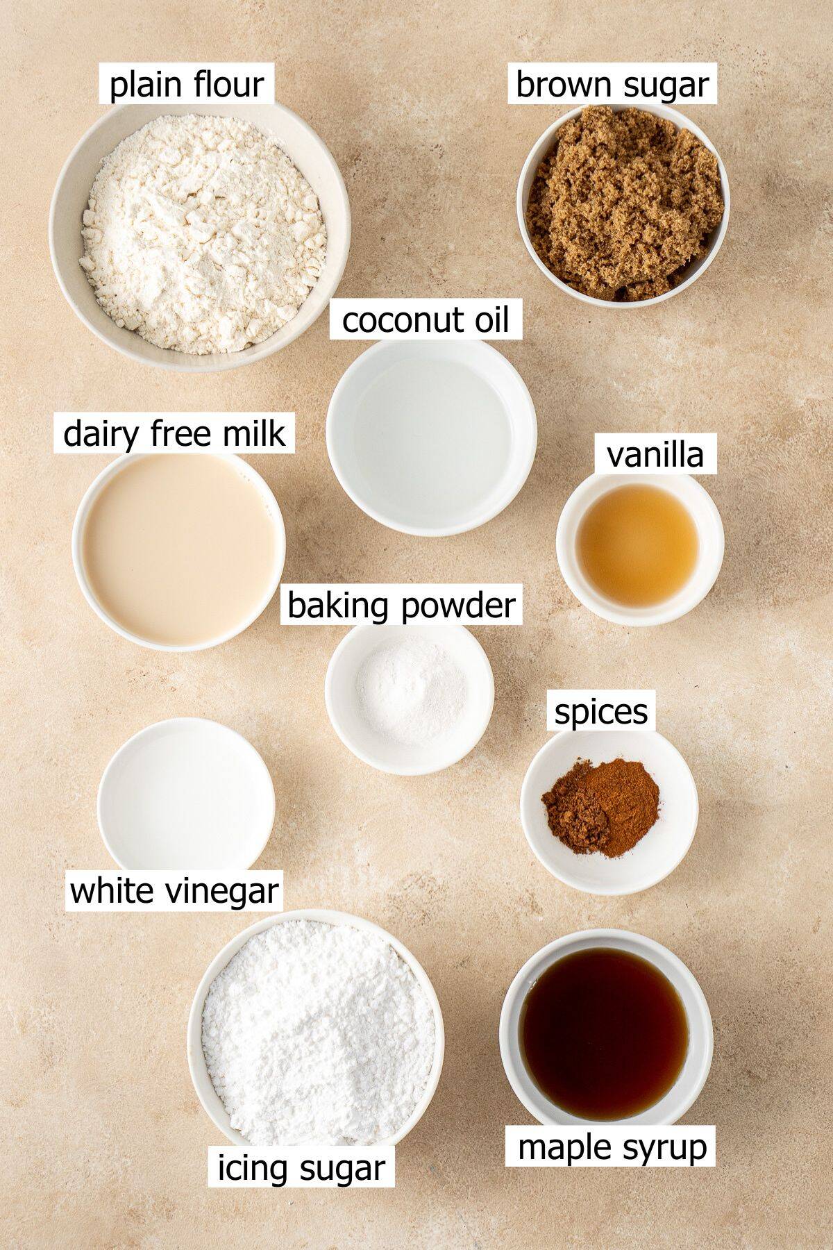 All ingredients needed to make maple doughnuts laid out in small bowls.