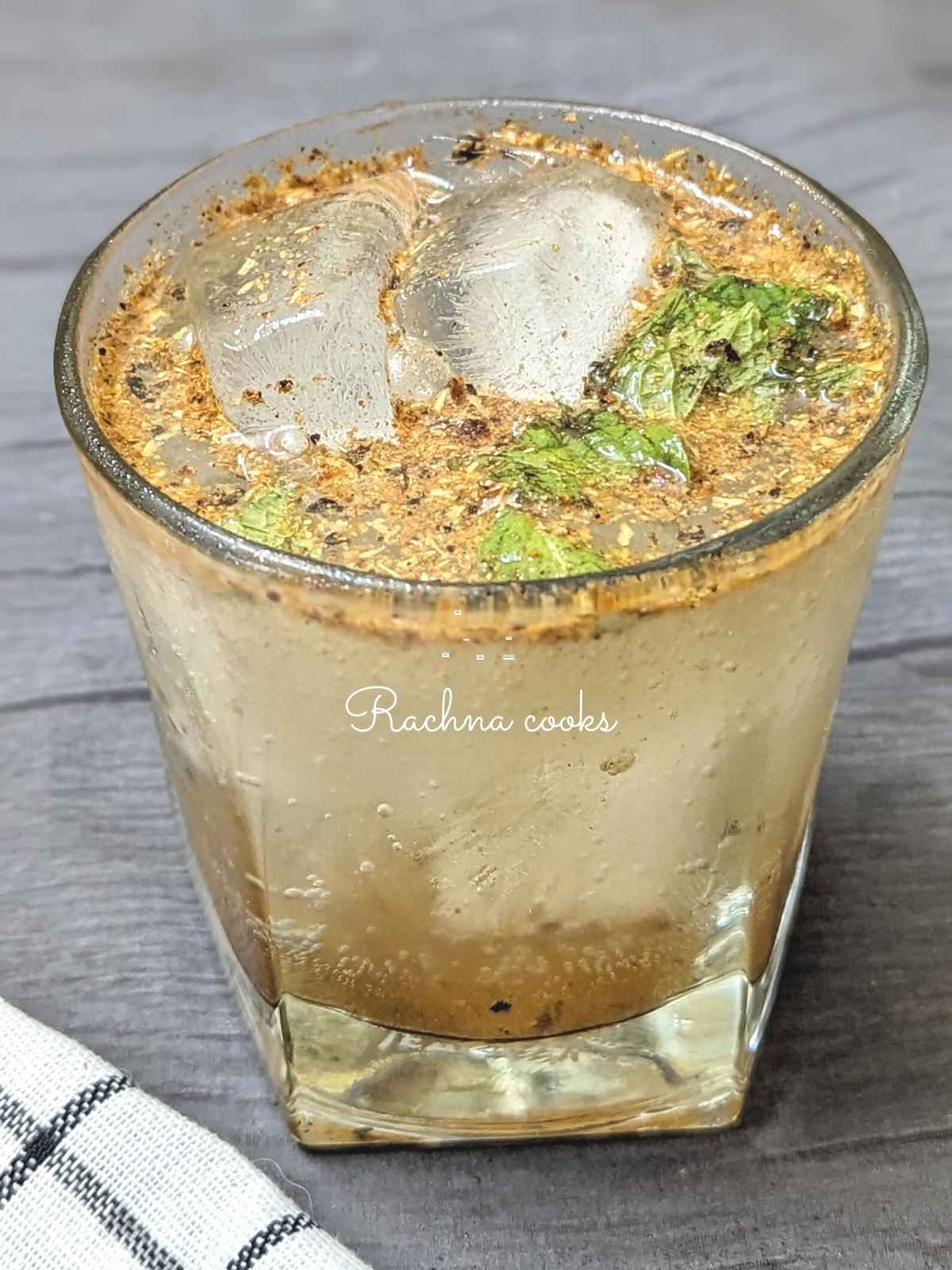 A glass fo amsala soda with ice cubes and a garnish of mint leaves.