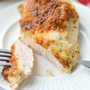 A fork taking a slice of chicken from a chicken breast.