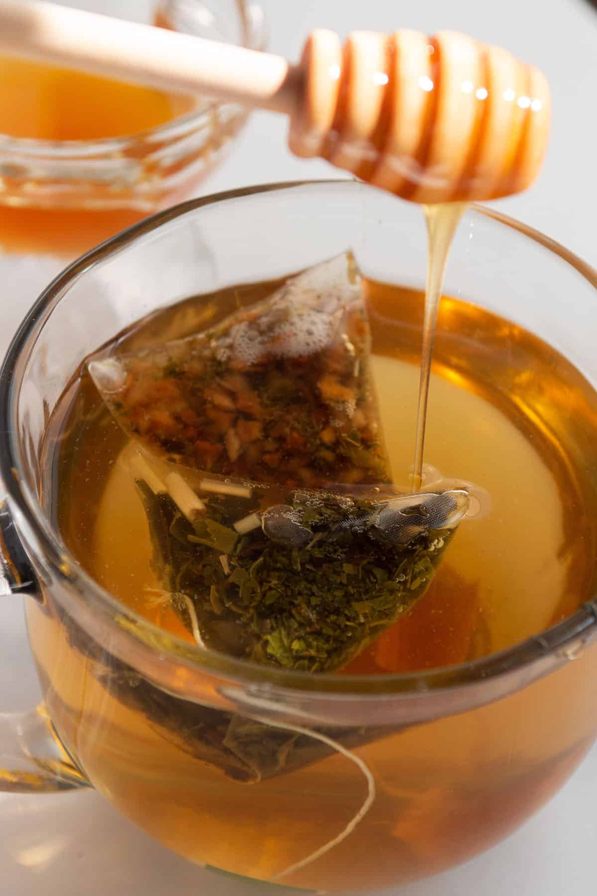 Honey being drizzled into a hot cup of tea. 