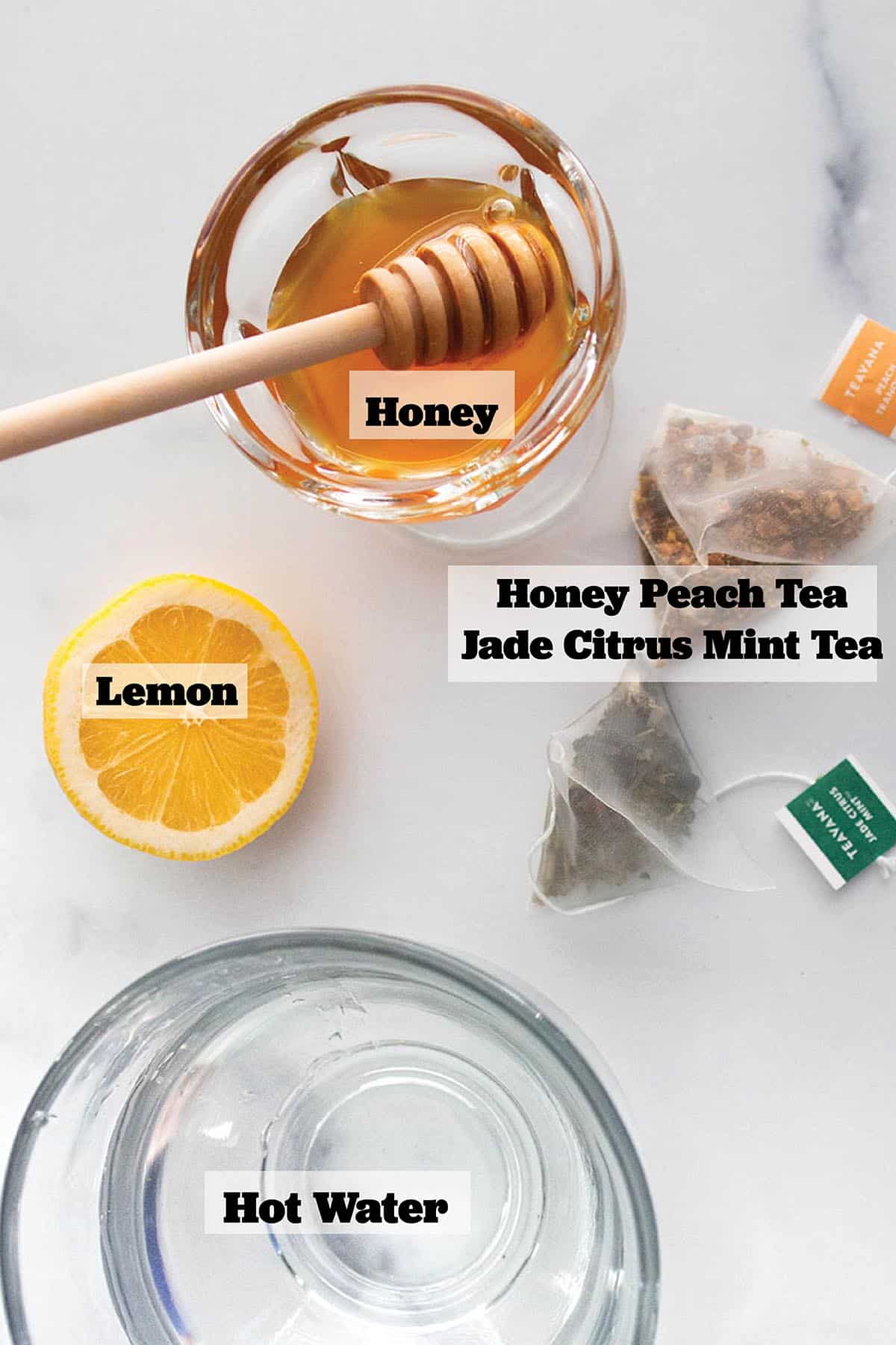 A cup of hot water, bowl of honey, half a lemon and two tea bags.
