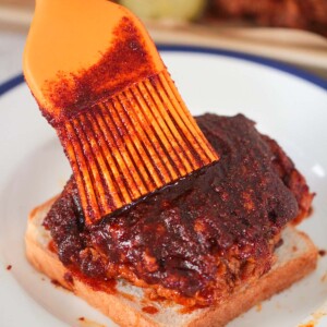 Nashville hot chicken on a slice of white bread and an orange brush.