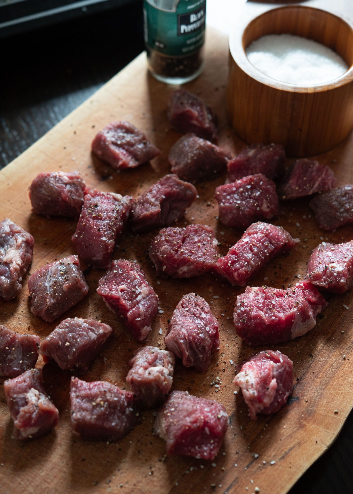 Seasoning stewing beef pieces with salt and pepper.