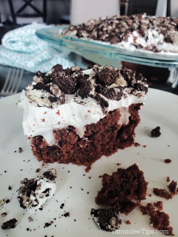 Oreo Poke Cake square on a white plate next to the baking dish. 