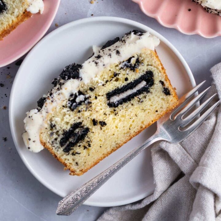 slice of oreo pound cake with vanilla cream icing on a plate with a fork