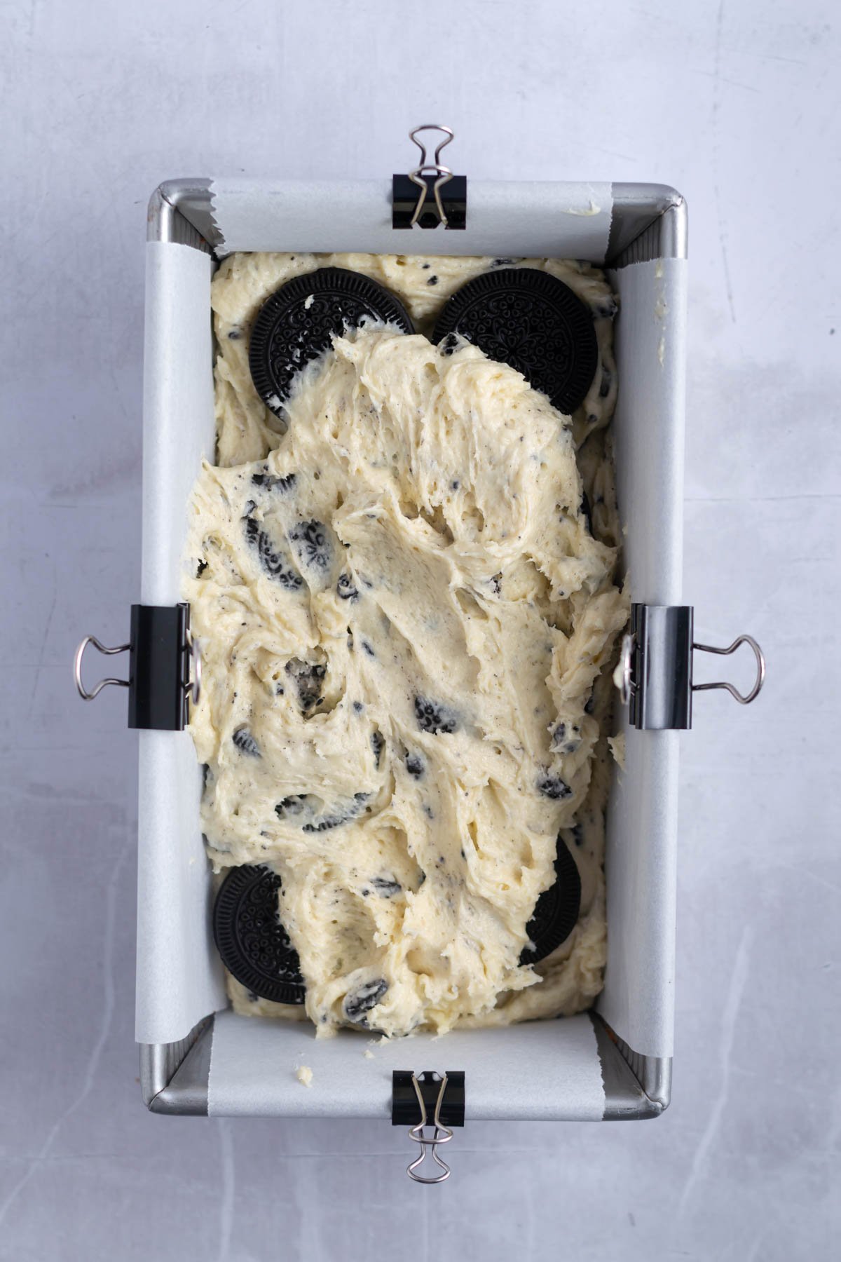 loaf pan with pound cake batter, showing whole chocolate sandwich cookies under another layer of cake batter