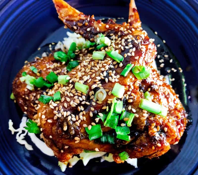 Crispy Baked Asian Chicken Wings on a plate with chopped green onions and baked sesame seeds for garnish.
