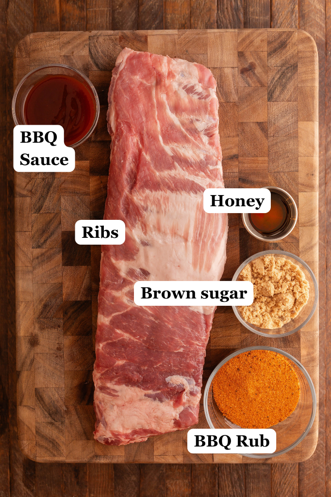 bowl of bbq sauce, bowl of bbq rub, bowl of brown sugar, pinch bowl of honey, and a slab of st. louis style ribs