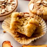 A photo of a peach almond streusel muffin with a bite taken out of it.