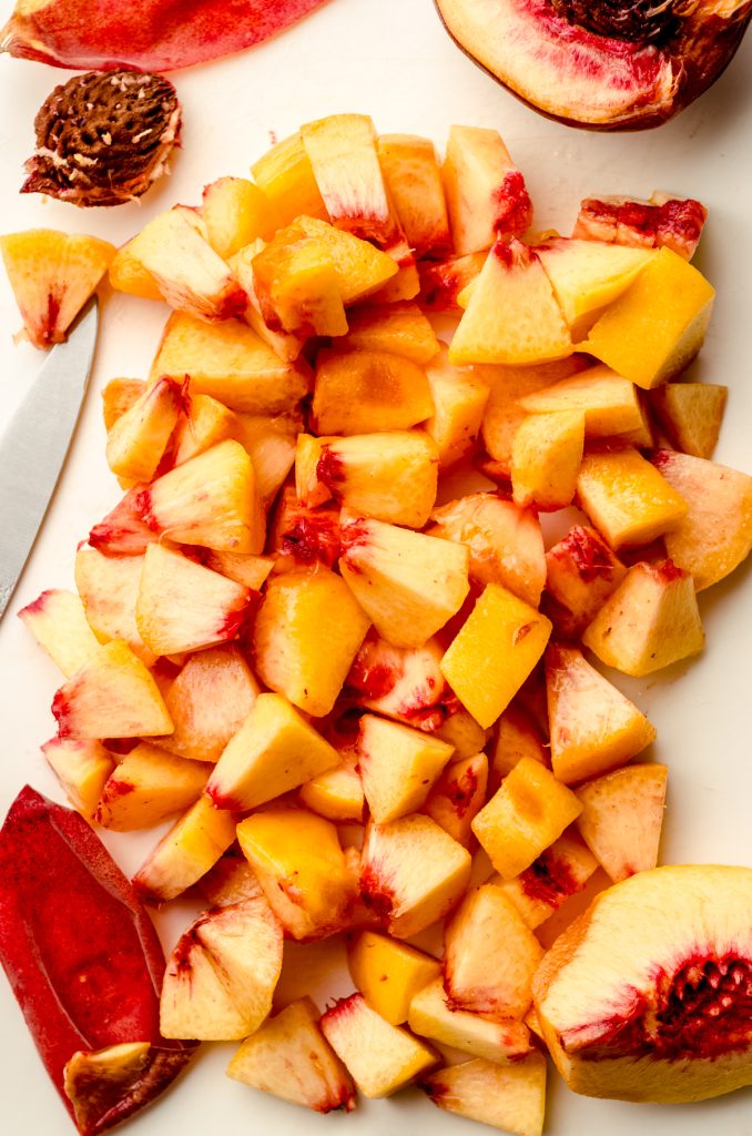 Aerial photo of chopped peaches on a cutting board.