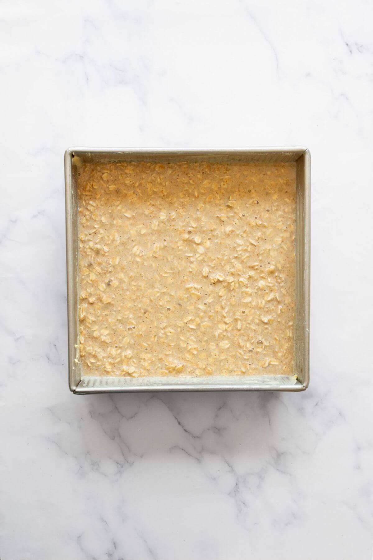 Unbaked peanut butter banana baked oatmeal batter spread evenly in a baking dish before going into the oven.
