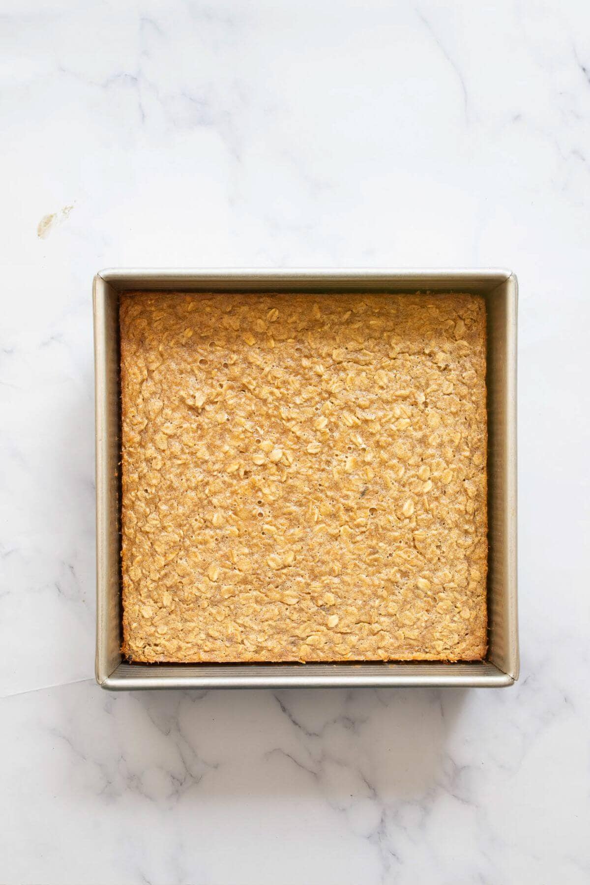 Freshly baked peanut butter banana oatmeal in a baking dish with a golden brown top.