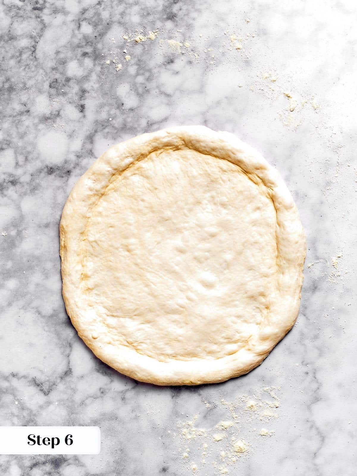 Pizza dough shaped into a circle on a floured surface.