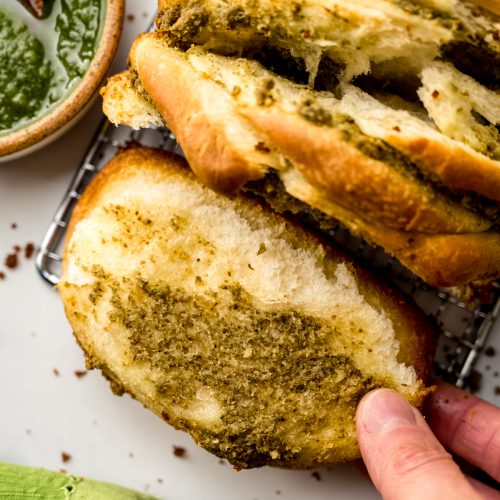 Aerial photo of pesto pull-apart bread that someone is pulling apart.