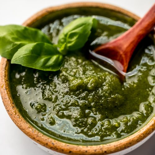 A bowl of homemade pesto with a small wooden spoon in it.