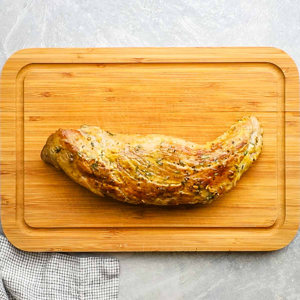 mustard spread on pork cut with thyme sprinkled on top