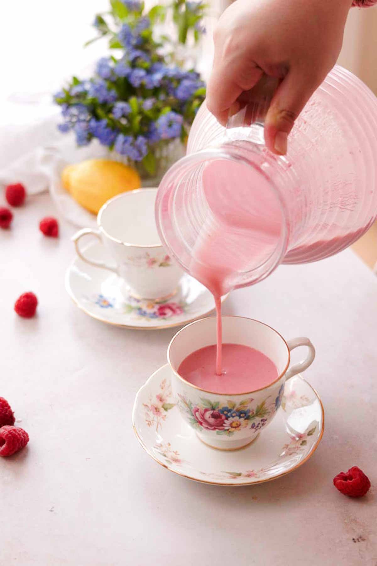 pouring raspberry posset out of the pitcher and into teacups on saucers