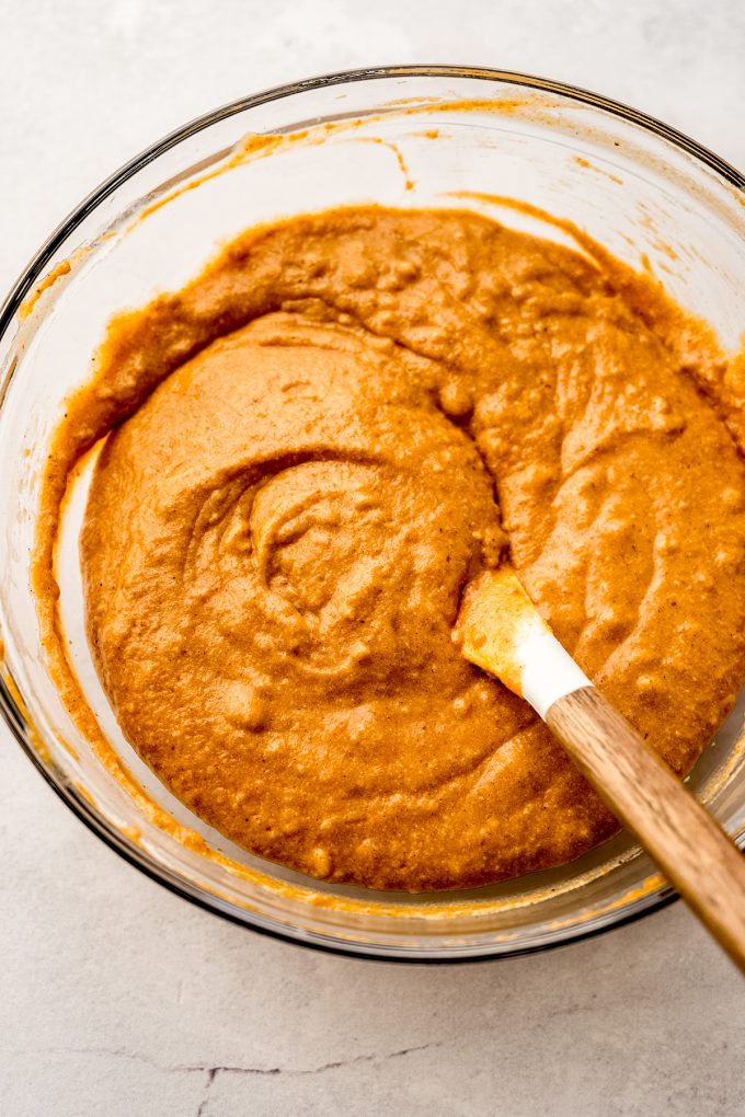 Pumpkin cake batter in a bowl being stirred with a spatula.