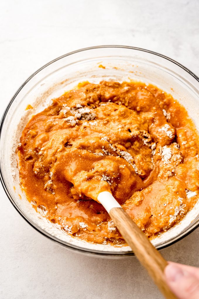 Pumpkin cake batter in a bowl being stirred with a spatula.