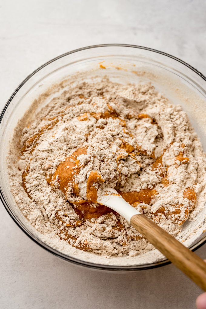 Pumpkin cake batter in a bowl being stirred with a spatula.