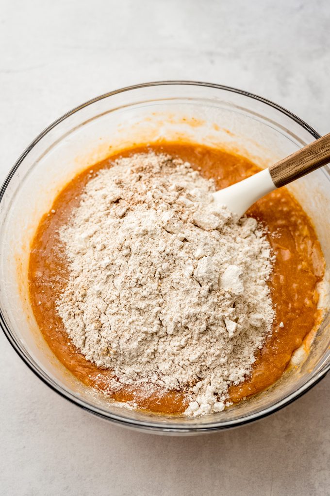 Pumpkin cake batter in a bowl being stirred with a spatula.