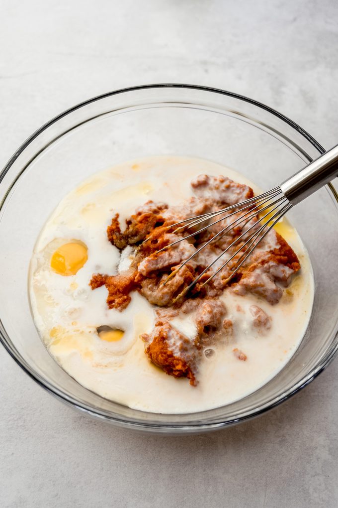 The wet ingredients for pumpkin cake in a bowl with a whisk.