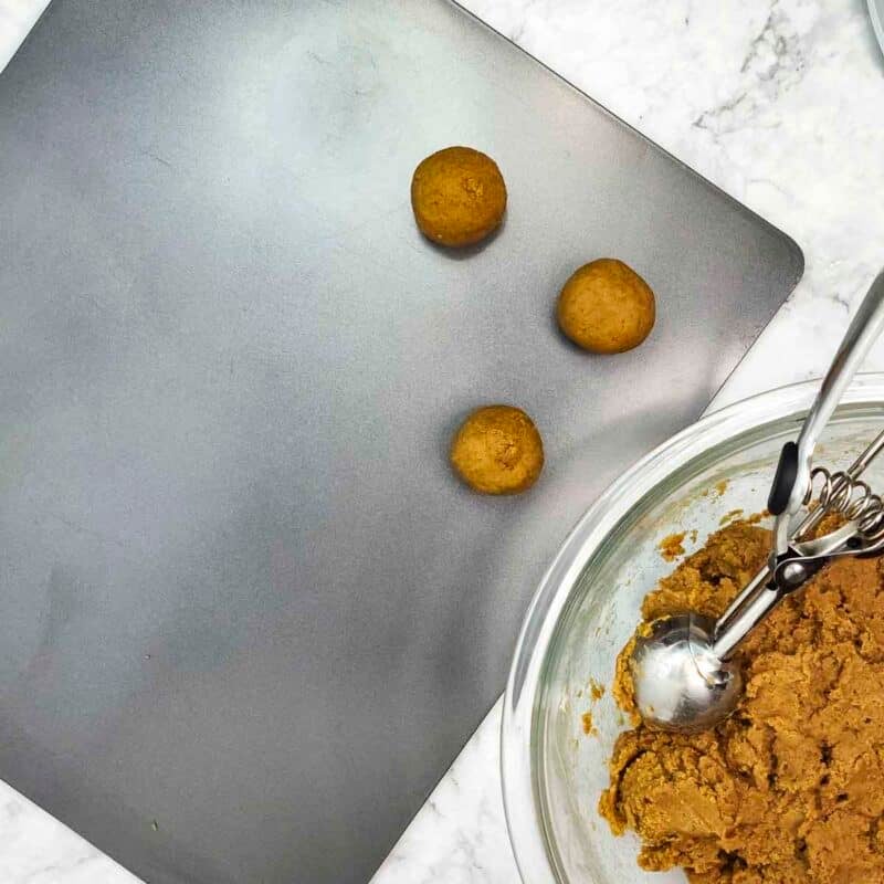 Overhead view of process shot 4 - using a cookie dough scoop, scoop the dough, roll it into balls, and place on a plate or baking sheet.