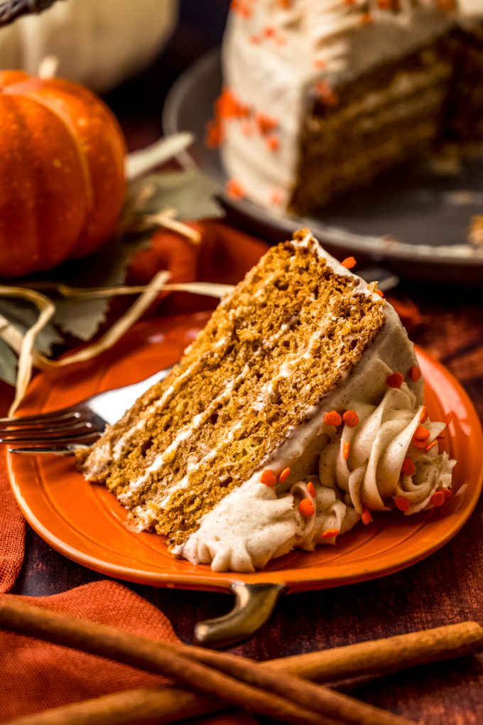 A slice of pumpkin layer cake on a plate with a fork.