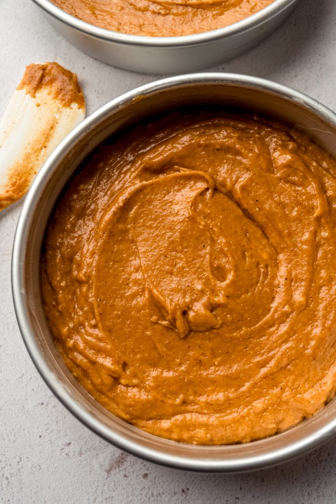 Aerial photo of a round cake pan with pumpkin cake batter in it.