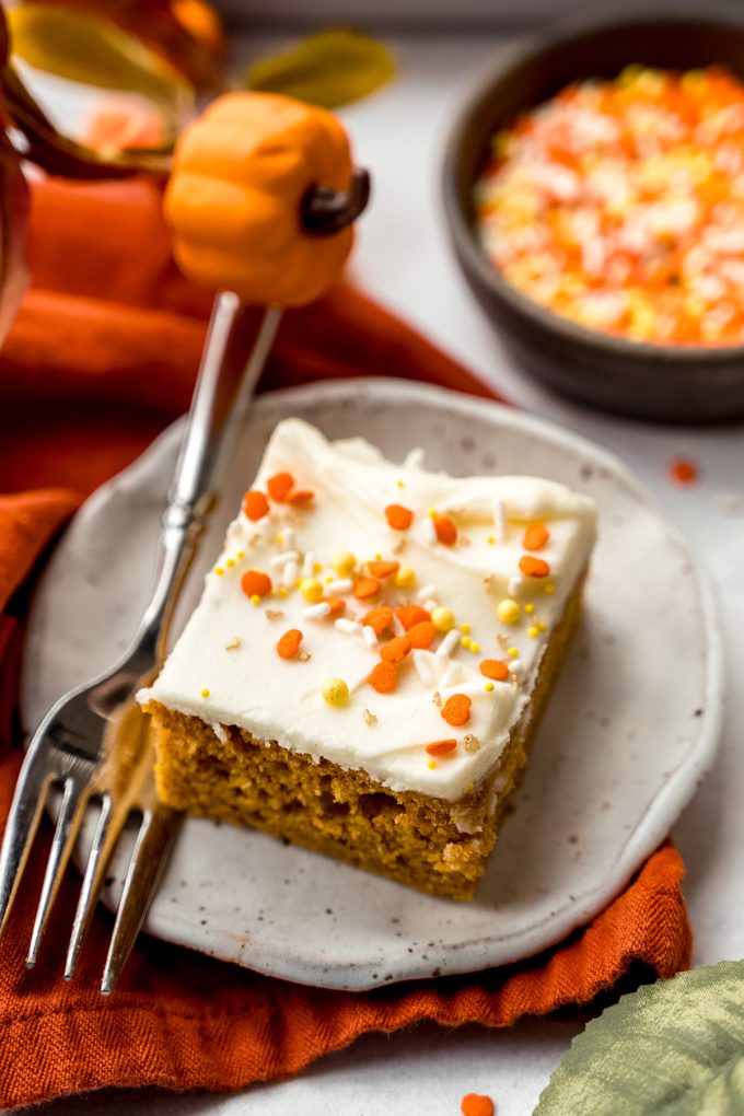 A slice of pumpkin sheet cake sitting on a plate with a fork.