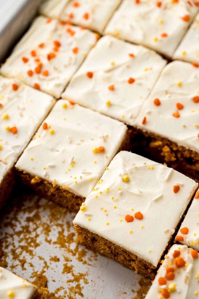 Sliced pumpkin sheet cake sitting in a baking pan.
