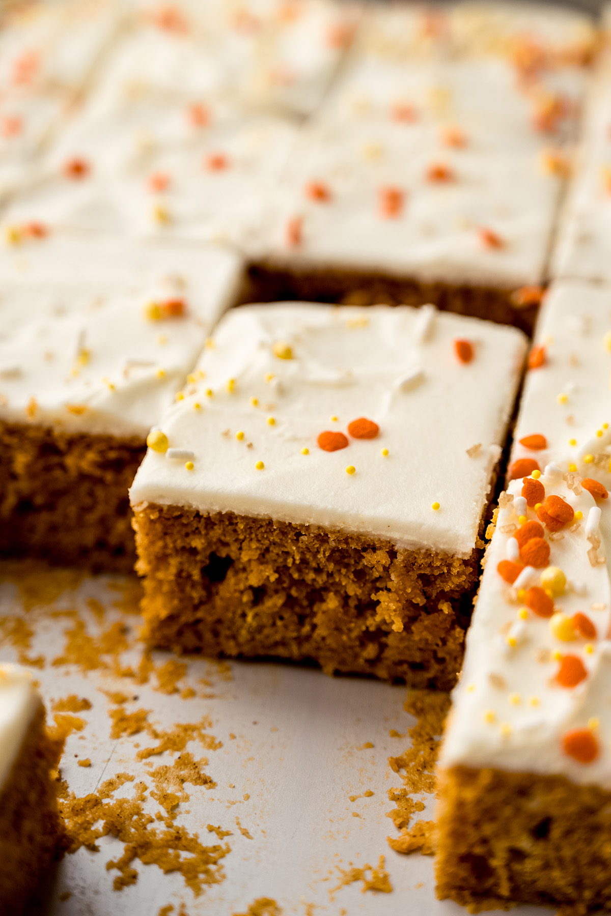 Sliced pumpkin sheet cake sitting in a baking pan.