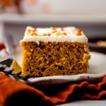 A slice of pumpkin sheet cake sitting on a plate with a fork.