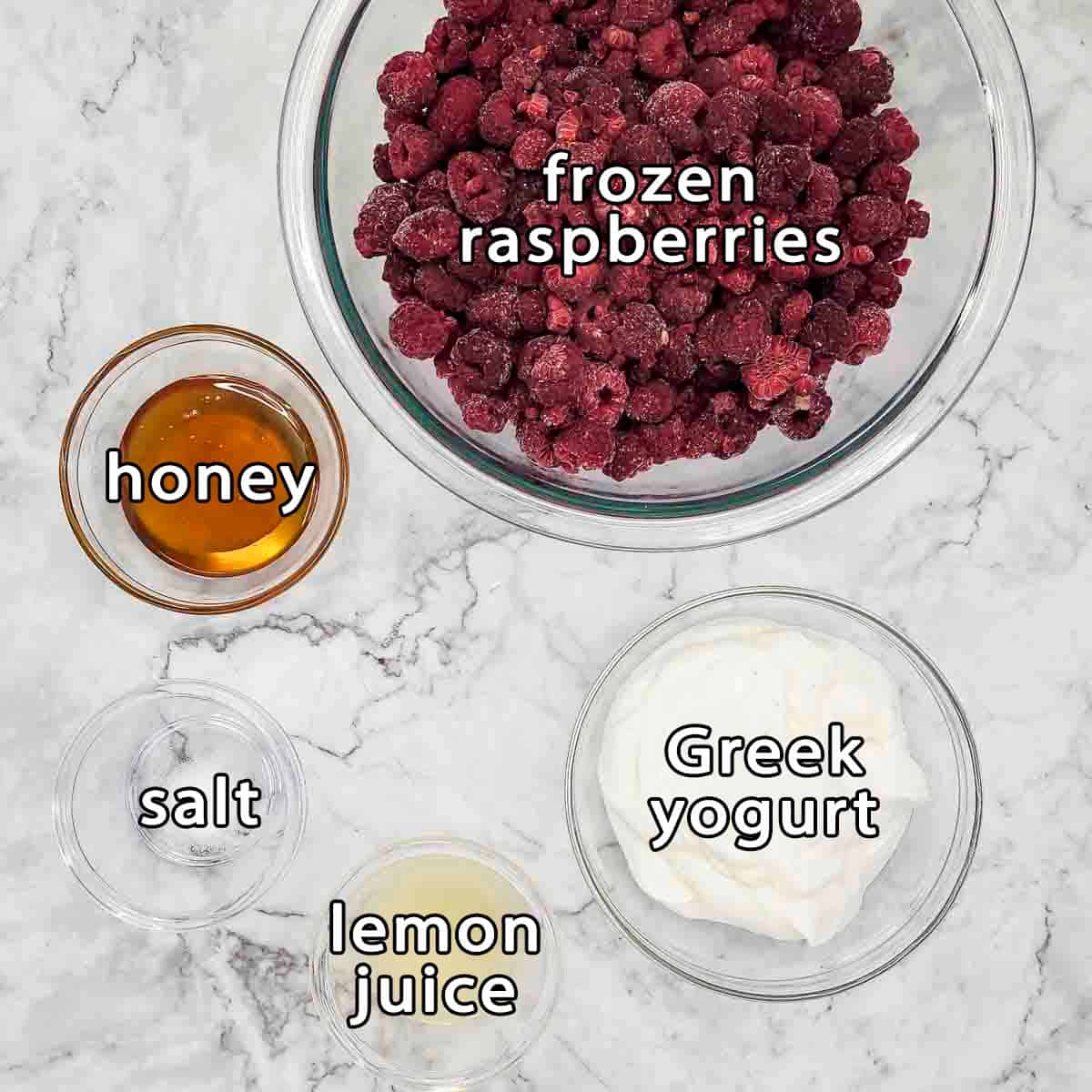 Overhead shot of ingredients - frozen raspberries, honey, greek yogurt, salt, and lemon juice.