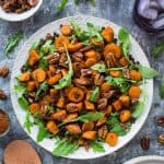 A plate of vegan roasted sweet potato, lentil and rocket salad with toasted pecans and pomegranate molasses dressing