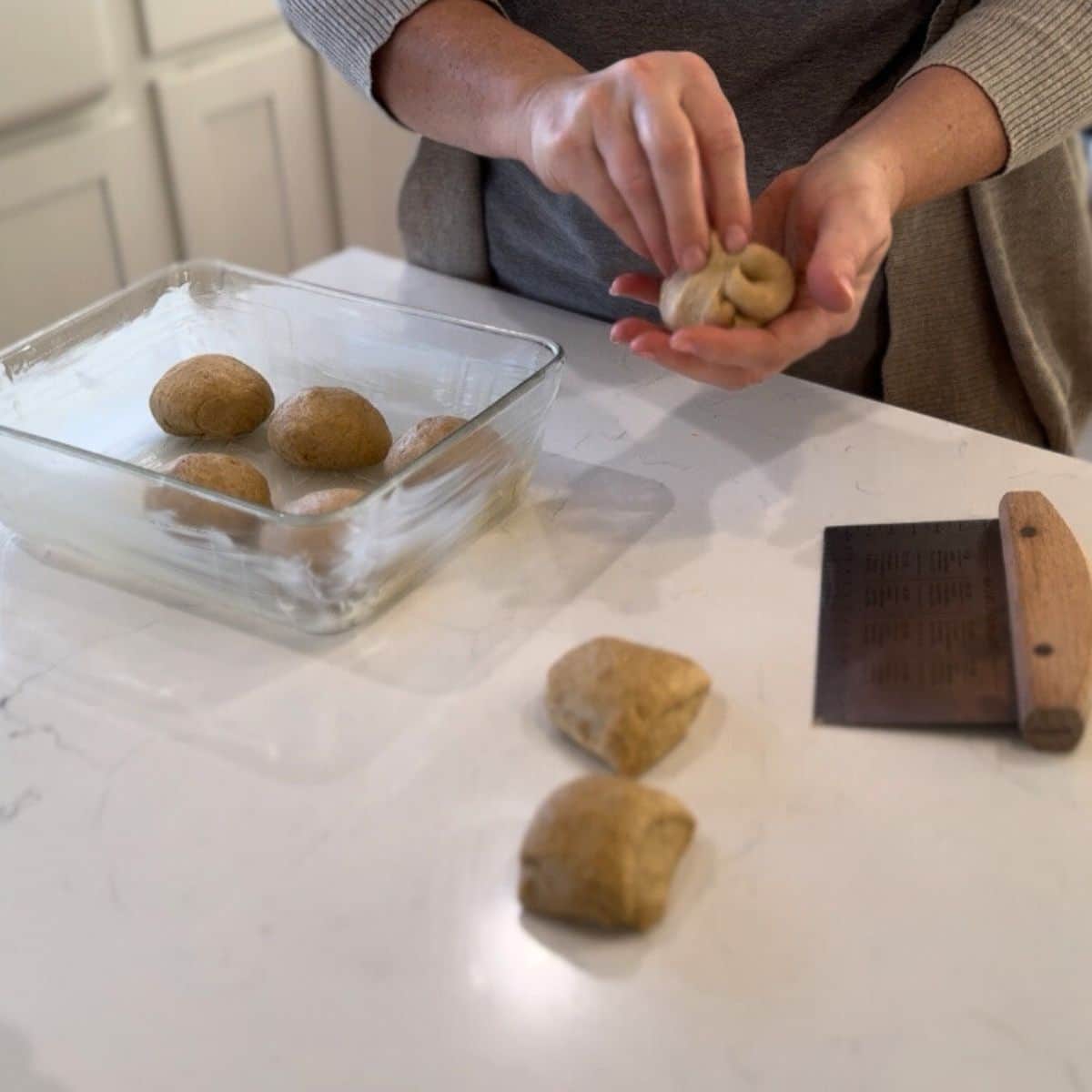 shaping einkorn sourdough roll dough into rolls, and placing them into baking dish